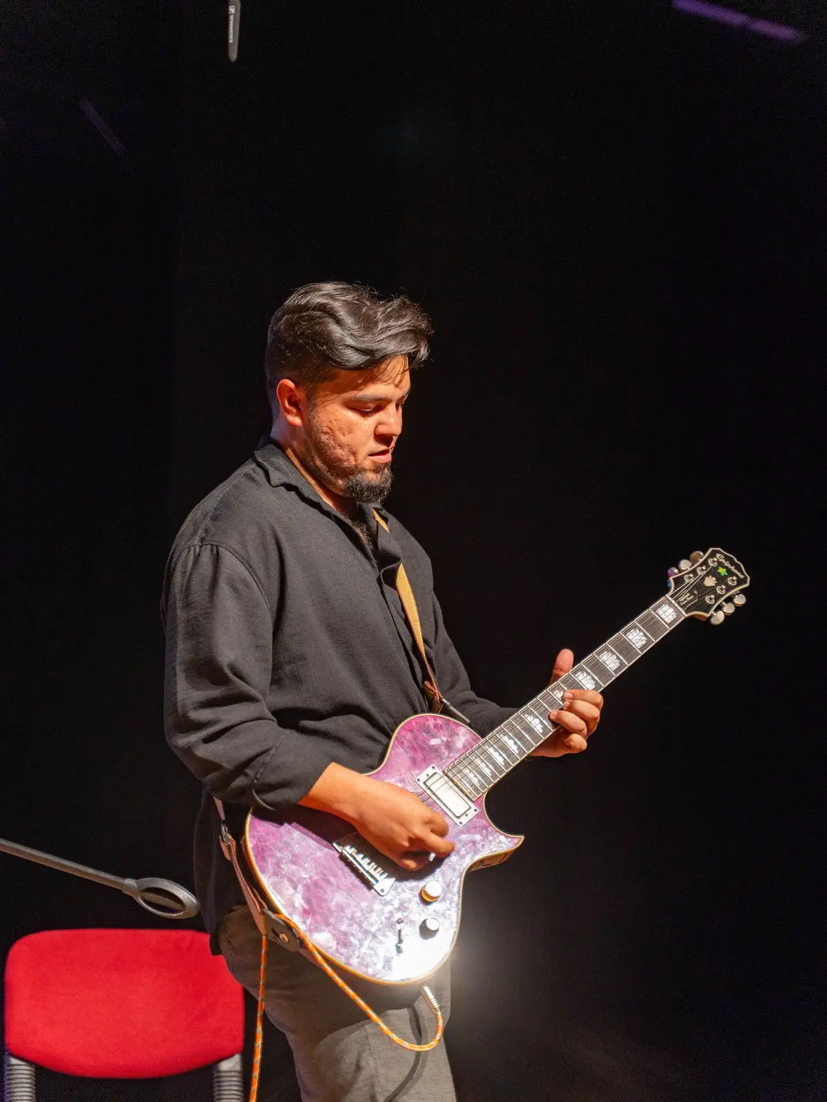 Sahnede elektro gitar çalan bir öğrenci