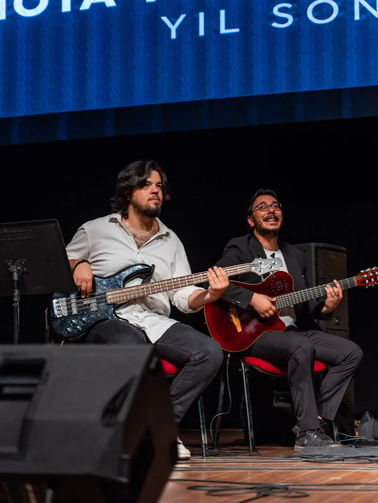 Sahnede birlikte elektro gitar çalan iki müzisyen