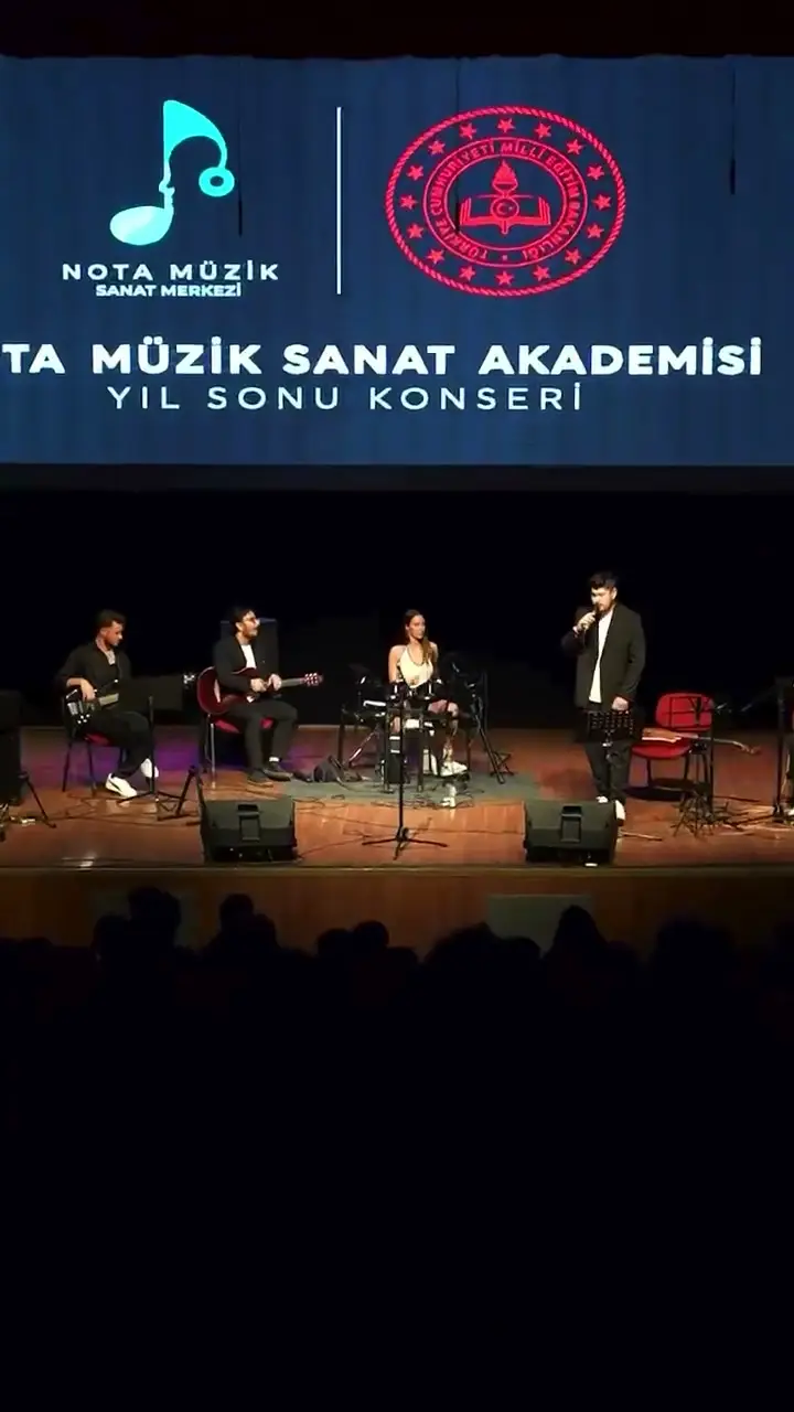Yıl sonu konserinde sahnedeki topluluk ve arkadaki konser afişi